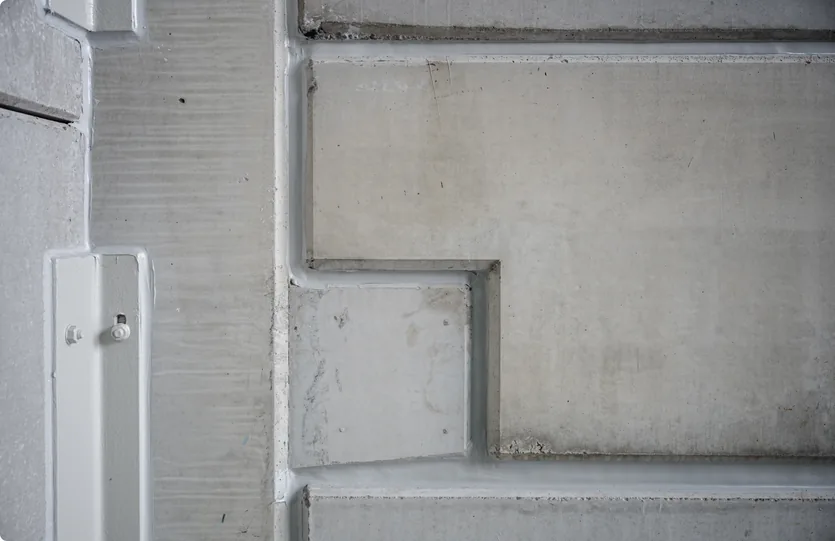 Aansluiting van de rode gevel op de grijze betonstructuur binnen