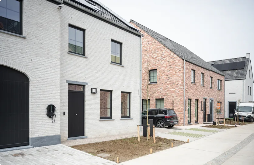 Straatzijde van het nieuwbouwproject met woningen in wit en rood metselwerk