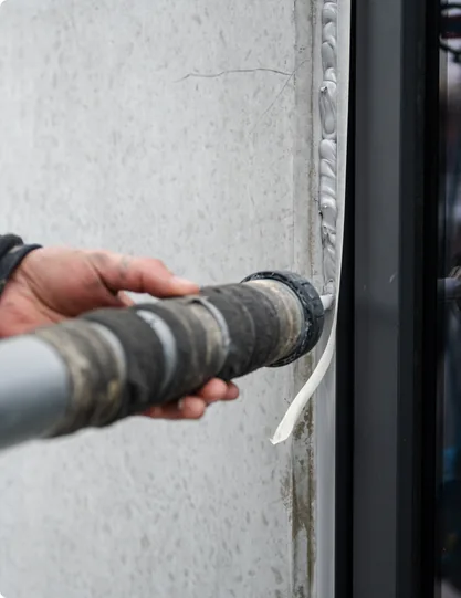 Kitpistool tijdens het aanbrengen van een elastische voeg tegen een betonpaneel