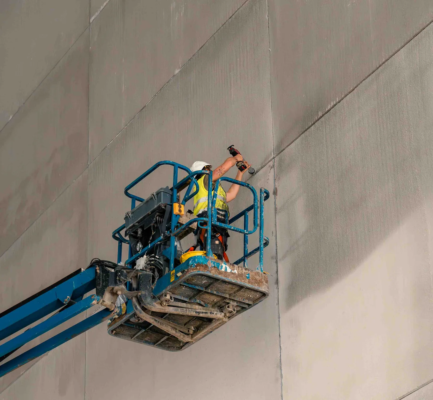Medewerker van Cammaert voegt een betonwand af vanuit een hoogwerker